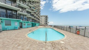 A pool area with a tiled deck, a lifeguard stand, and a view of the ocean.