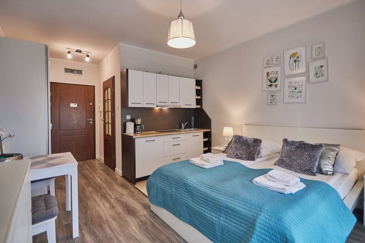 Une chambre d’hôtel de taille réduite, comprenant un lit, une table de chevet et une kitchenette.