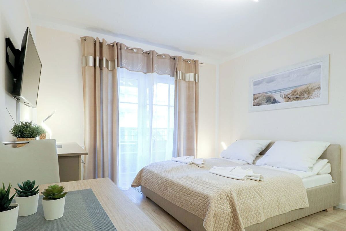 Une chambre à coucher avec un lit, un bureau, une chaise et une fenêtre avec des rideaux.