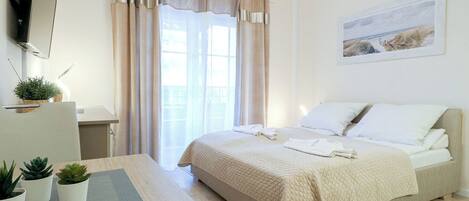 Un dormitorio con cama, escritorio, silla y ventana con cortinas.
