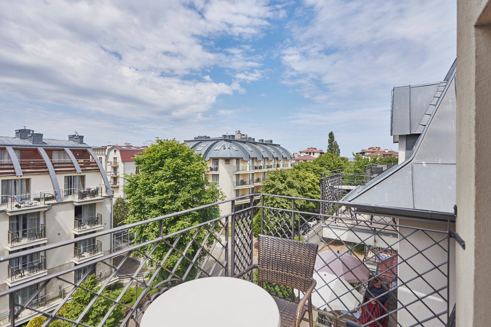 A residential building with multiple balconies, a clear sky, and surrounding greenery.