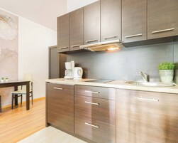 Una cocina moderna con armarios de madera, un lavamanos de acero inoxidable y una cafetera.