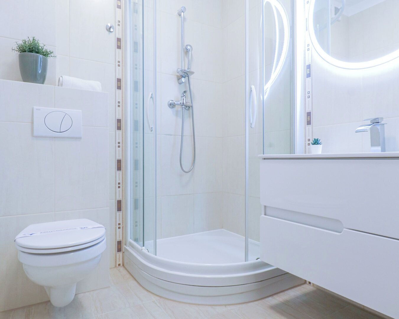 A modern bathroom with a glass-enclosed shower, a toilet, and a vanity with a mirror.