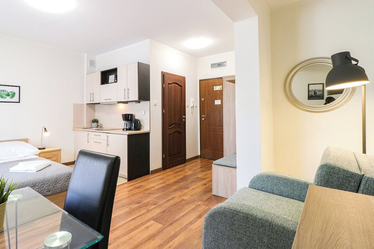 Une chambre d’hôtel compacte comprenant un coin cuisine, un espace repas, un canapé et un miroir.