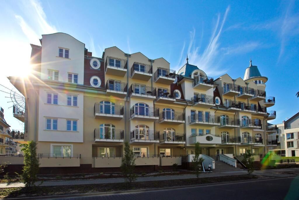 Et hotel med flere etager, altaner, en central trappe og en klar himmel.