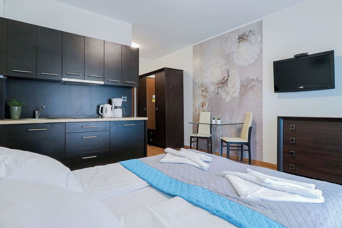 Une chambre d’hôtel moderne équipée d’un lit, d’une petite kitchenette, d’un coin repas et d’un téléviseur.