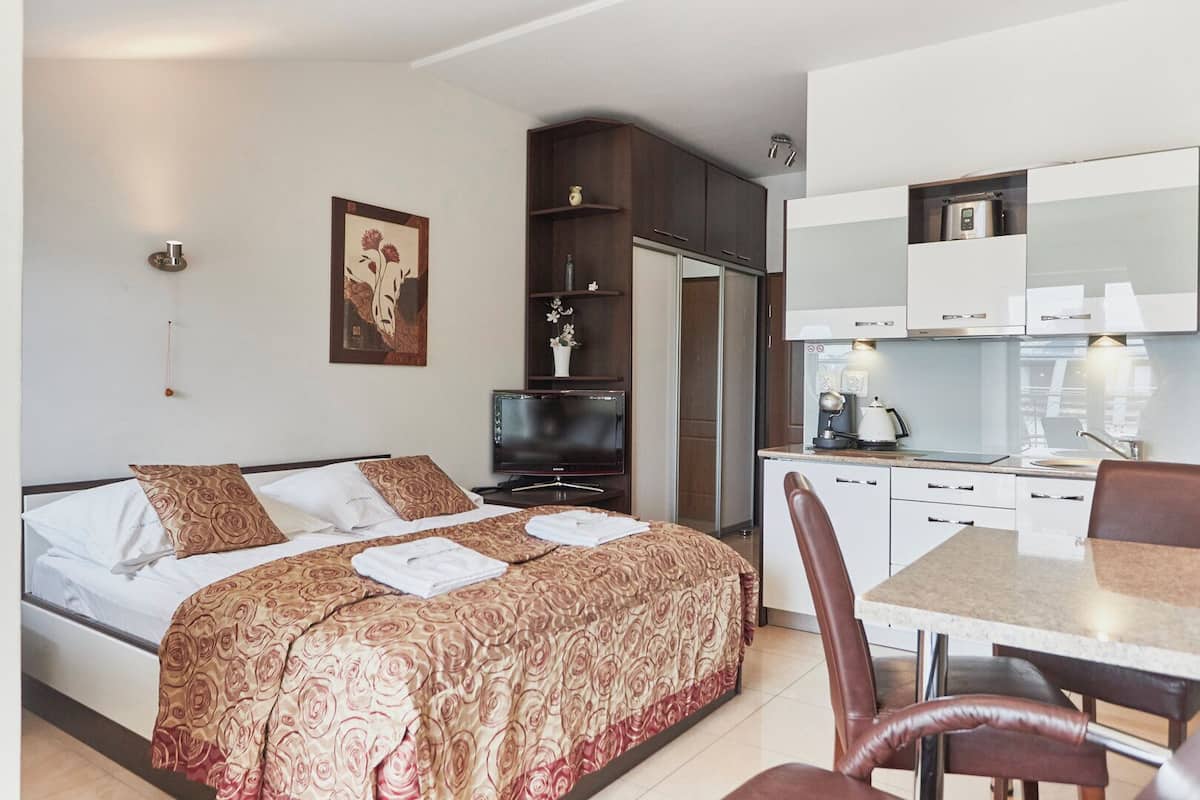 Une chambre d’hôtel équipée d’un lit, d’un bureau, d’une chaise, d’une télévision et d’une kitchenette.