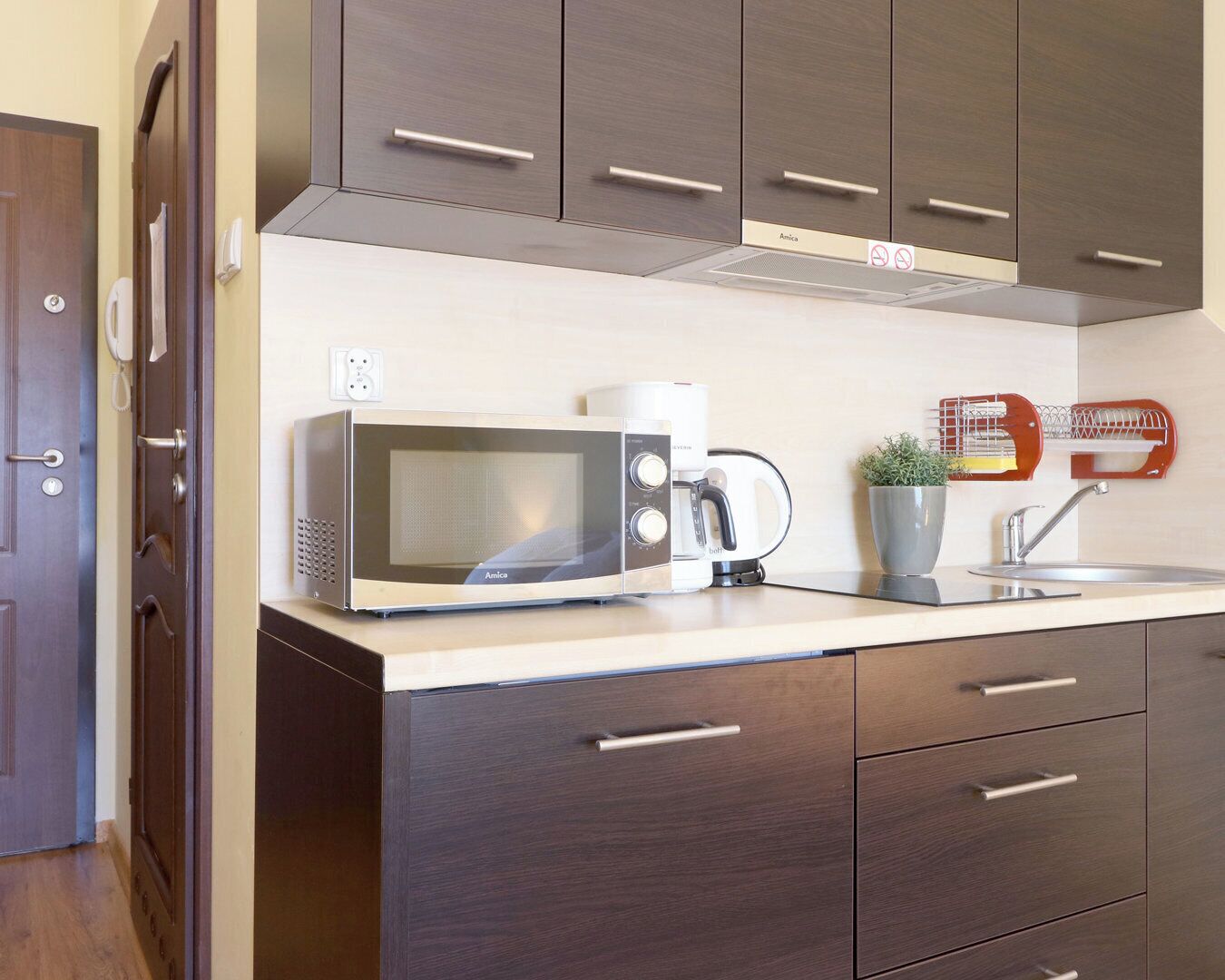A modern kitchen with a built-in microwave, coffee maker, and a small plant on the counter.