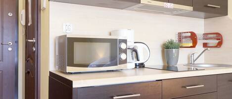 A modern kitchen with a built-in microwave, coffee maker, and a small plant on the counter.