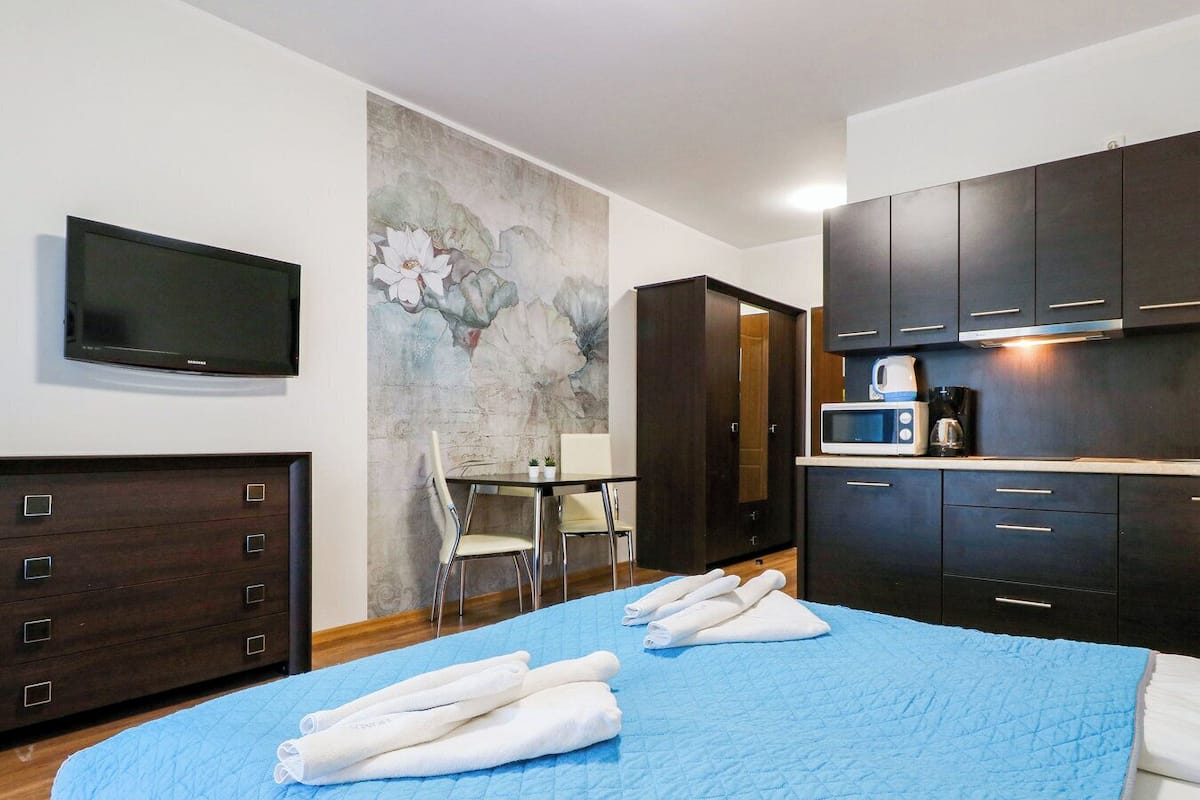 Une chambre d’hôtel équipée d’un lit, d’un bureau, d’une chaise, d’un téléviseur à écran plat, d’armoires en bois foncé et d’un four à micro-ondes.