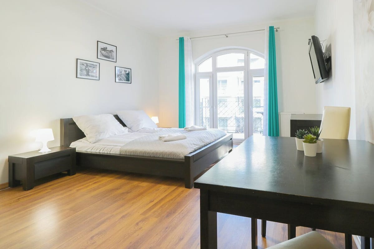 Une chambre moderne avec un lit, des tables de chevet, un bureau et une vue sur l’extérieur.