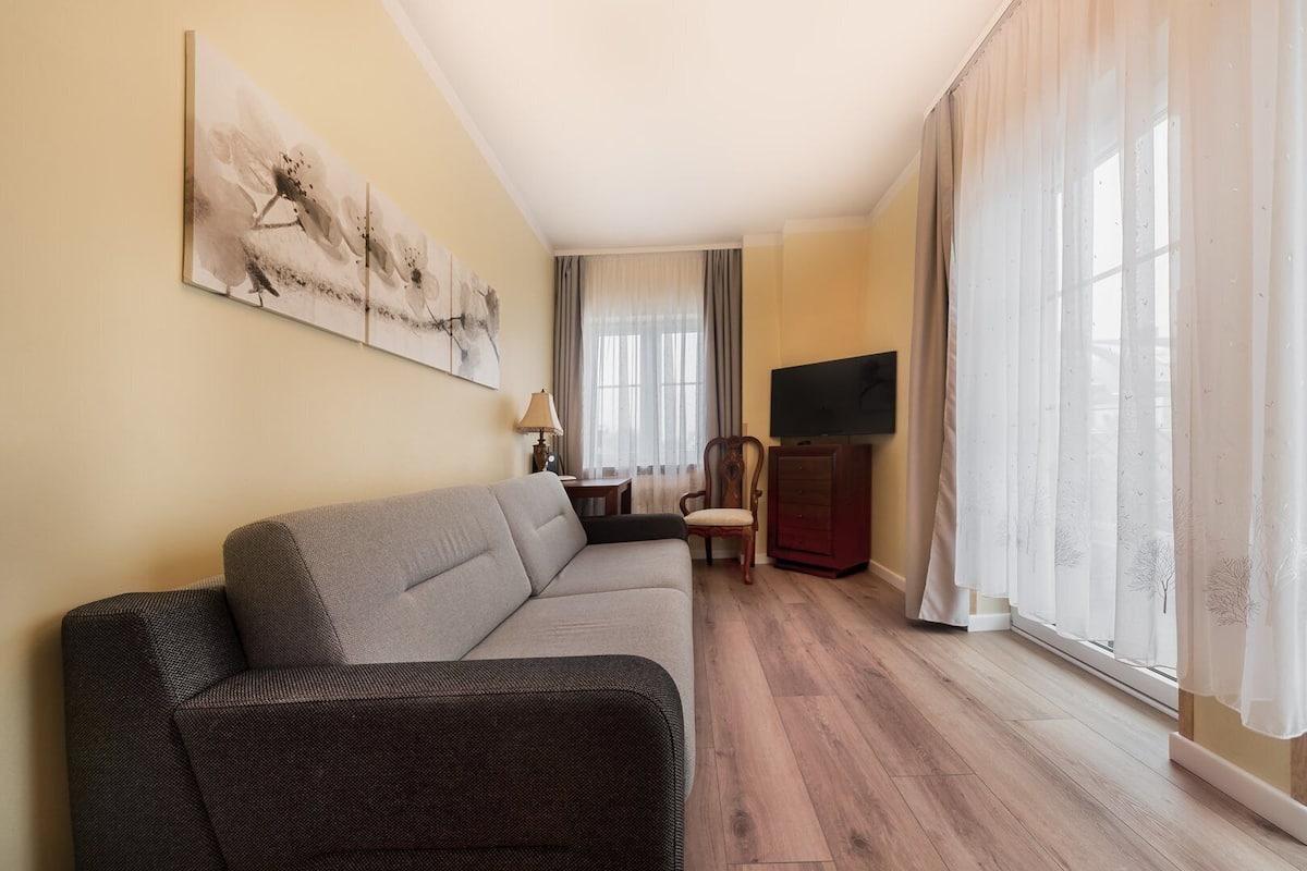 Un salon avec un canapé, un fauteuil, un téléviseur et un tableau accroché au mur.