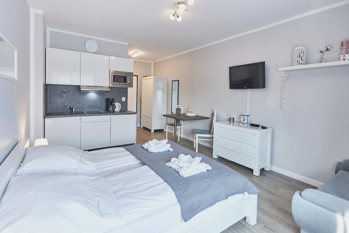 Une chambre d’hôtel moderne équipée d’un lit, d’un bureau, d’une kitchenette et d’un téléviseur.