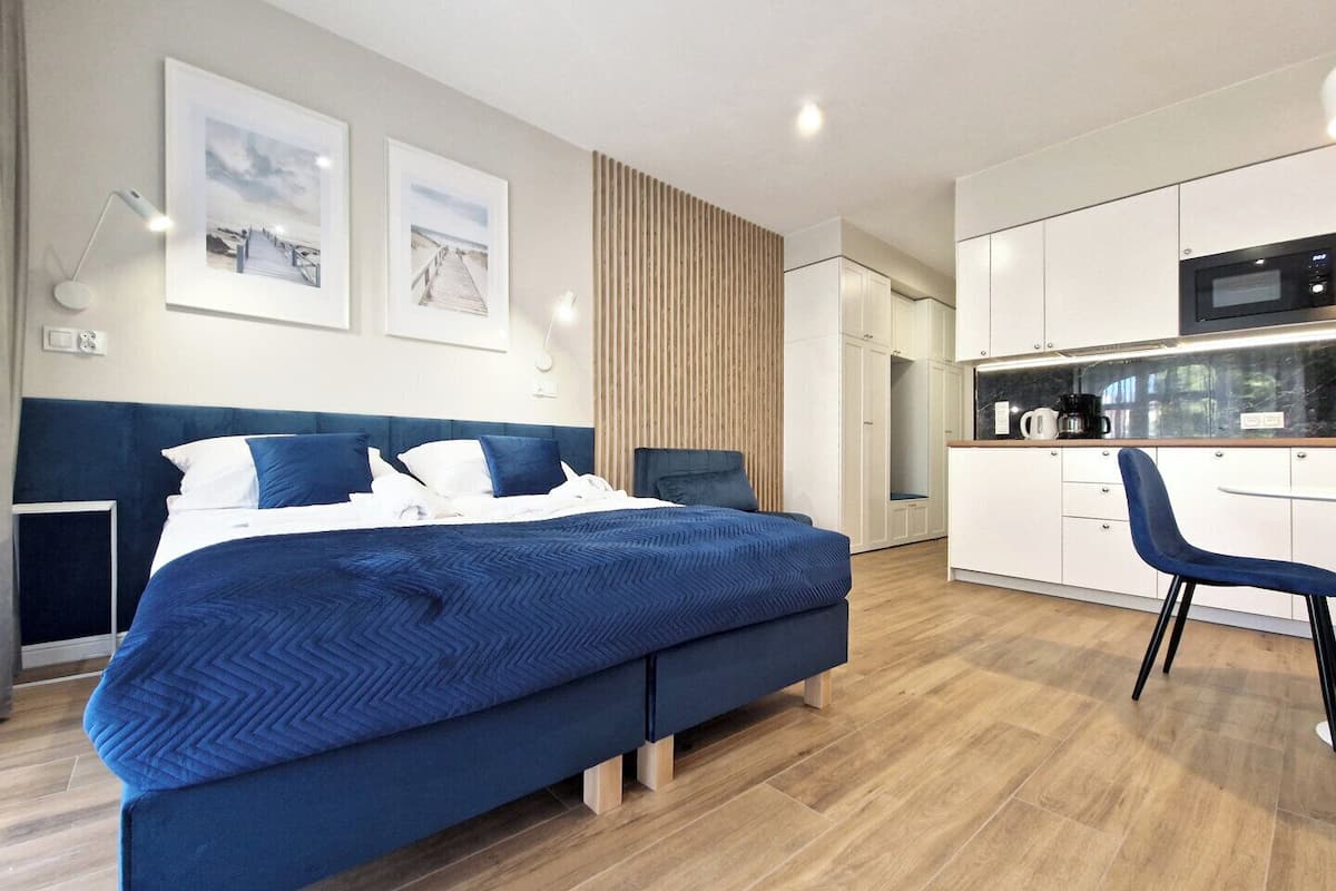 Une chambre moderne avec un grand lit, un bureau et un coin cuisine.