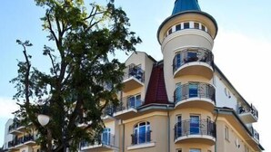 A multi-story building with balconies, a central tower, and a tree in front. - Regina Maris by Baltic Home (Swinoujscie)