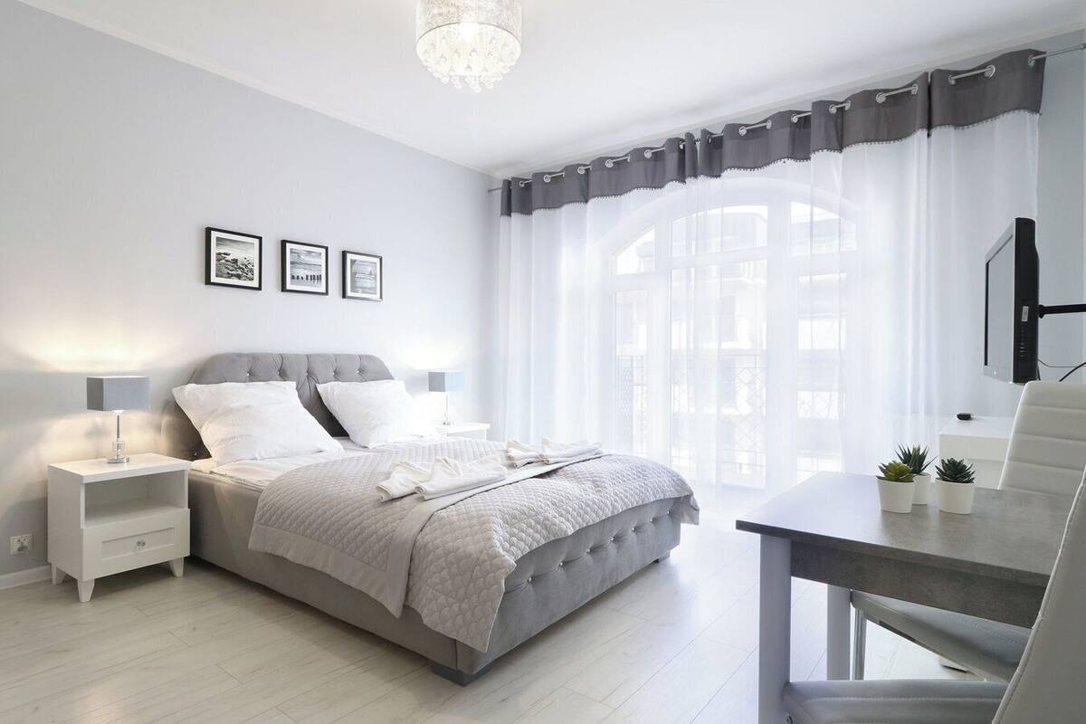 Une chambre à coucher moderne avec un lit, des tables de chevet, un bureau et une chaise.