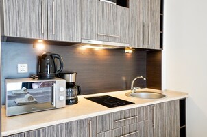 Una kitchenette con microondas integrado, cafetera y cocina eléctrica.