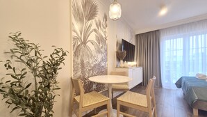 A modern hotel room with a dining area, a bed, a TV, and a large window with curtains. - Regina Maris by Baltic Home (Swinoujscie)