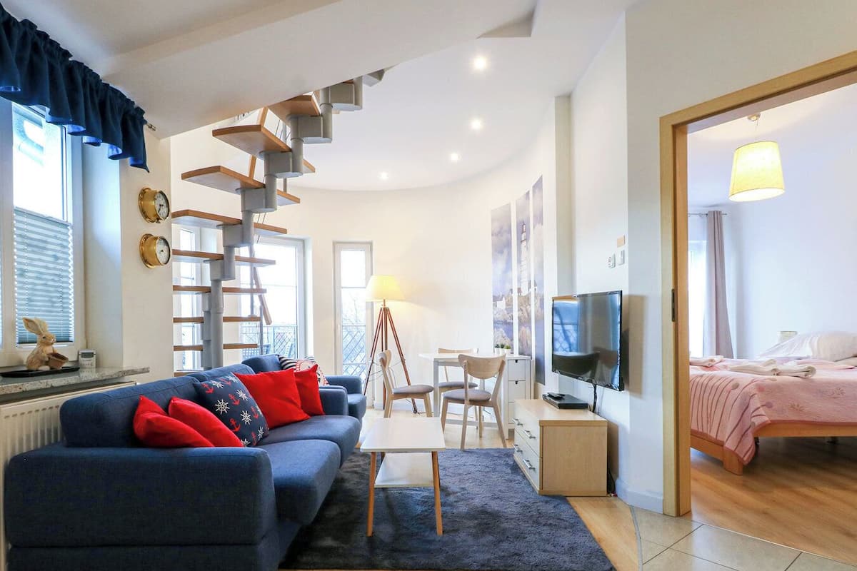 Un salon moderne avec un canapé bleu, un escalier en bois et un téléviseur.