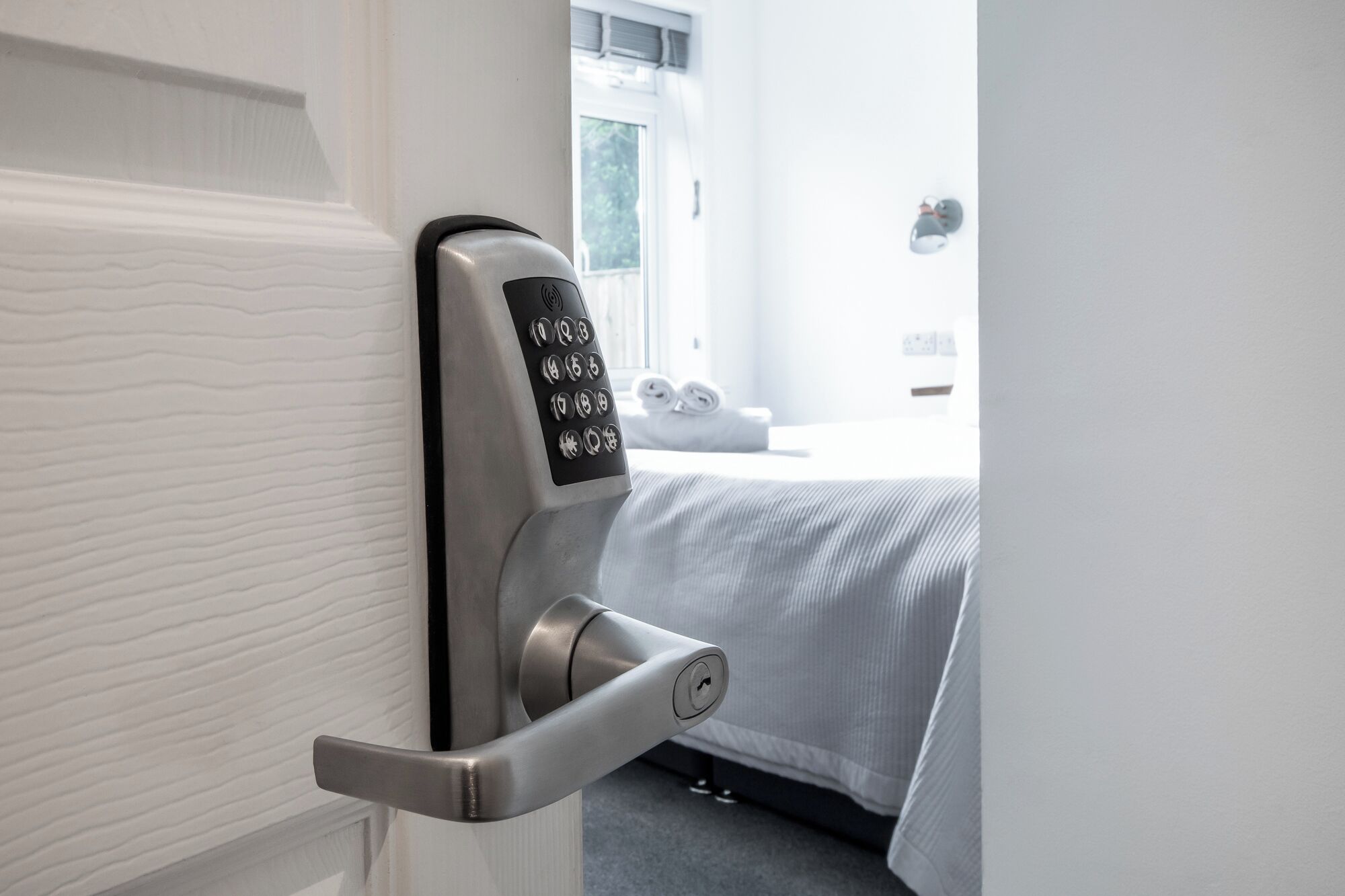 A modern hotel room door with a digital keypad lock and a keyhole.