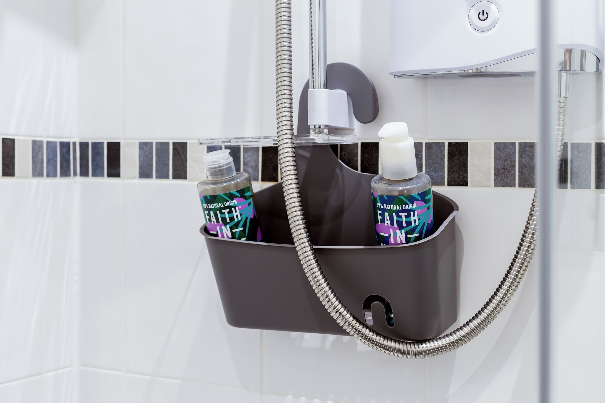Area doccia con porta asciugamani nero che contiene due flaconi di shampoo e balsamo 'Faith-in'.