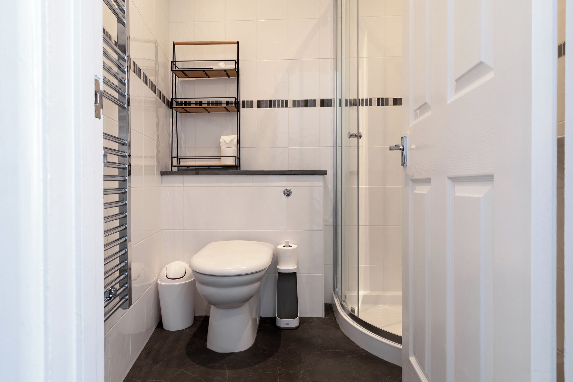 Een moderne badkamer met toilet, bidet en een douche met glazen wanden.