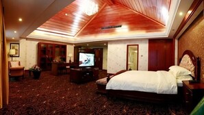 Een hotelkamer met een groot bed, een televisie, een bureau met stoel en een vloerkleed.