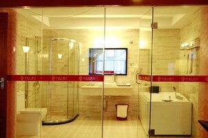 Un baño de hotel con ducha de vidrio, lavamanos y espejo.