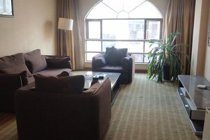 Una sala de estar con sofá, sillón, mesa de centro y mueble para televisión.