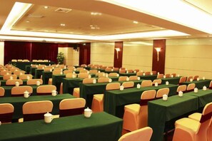 Une salle de conférence dotée de plusieurs tables et de nombreuses chaises, disposées en rangées.