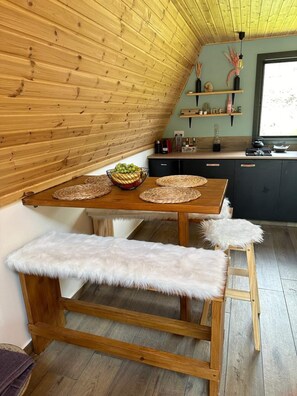 A cozy kitchen with a wooden table, a bench, and a loft-style ceiling. - Scenic Mountain Getaway for Couples with Pool Access (Arakapas)
