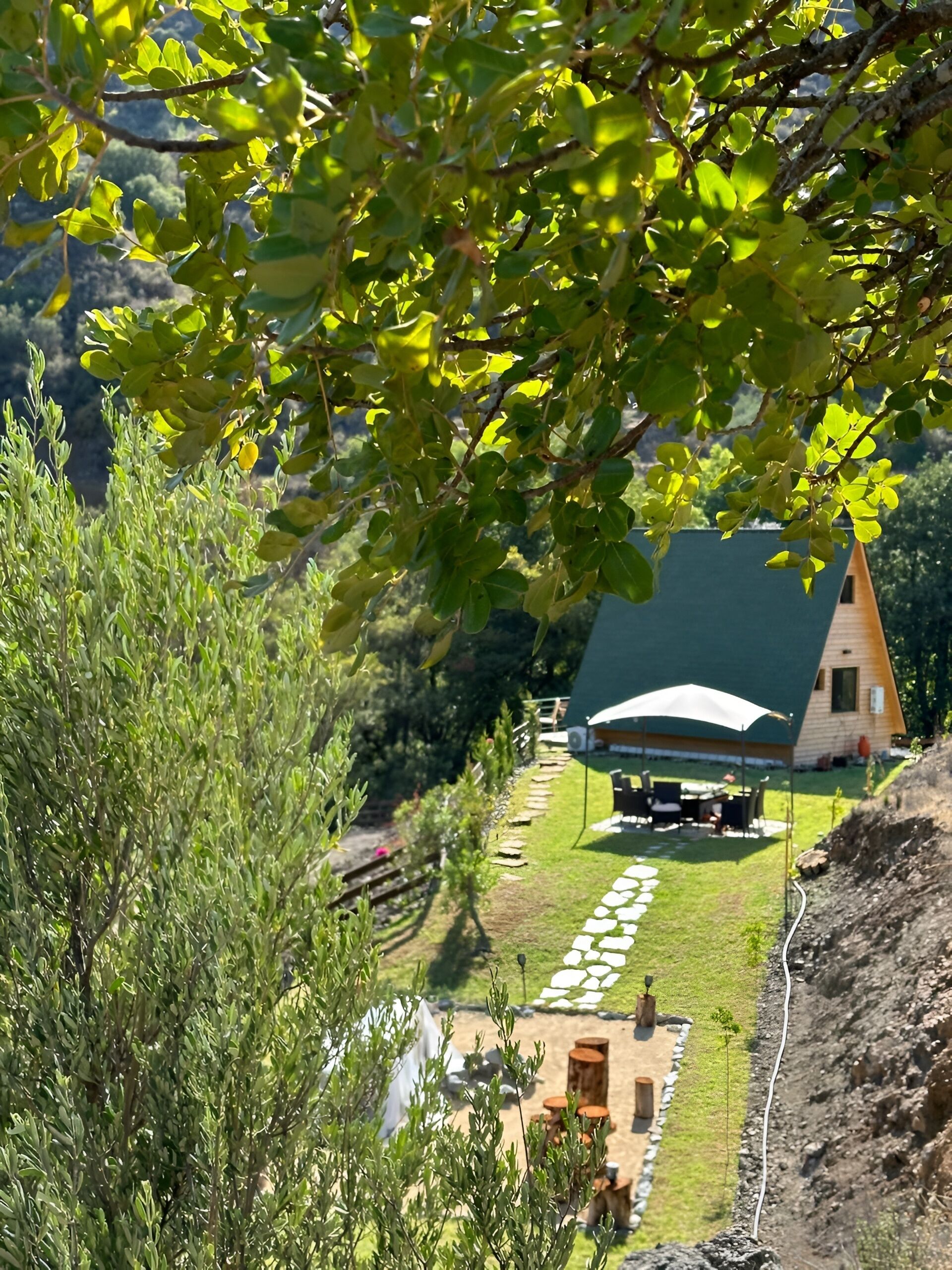 Ein rustikales Blockhaus mit grüner Dachdeckung, umgeben von einem gepflegten Garten und einem Kiesweg.