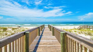 Un paseo marítimo de madera que conduce a una playa con cielos despejados.
