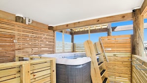A wooden spa area with a hot tub, wooden benches, and a pergola structure.
