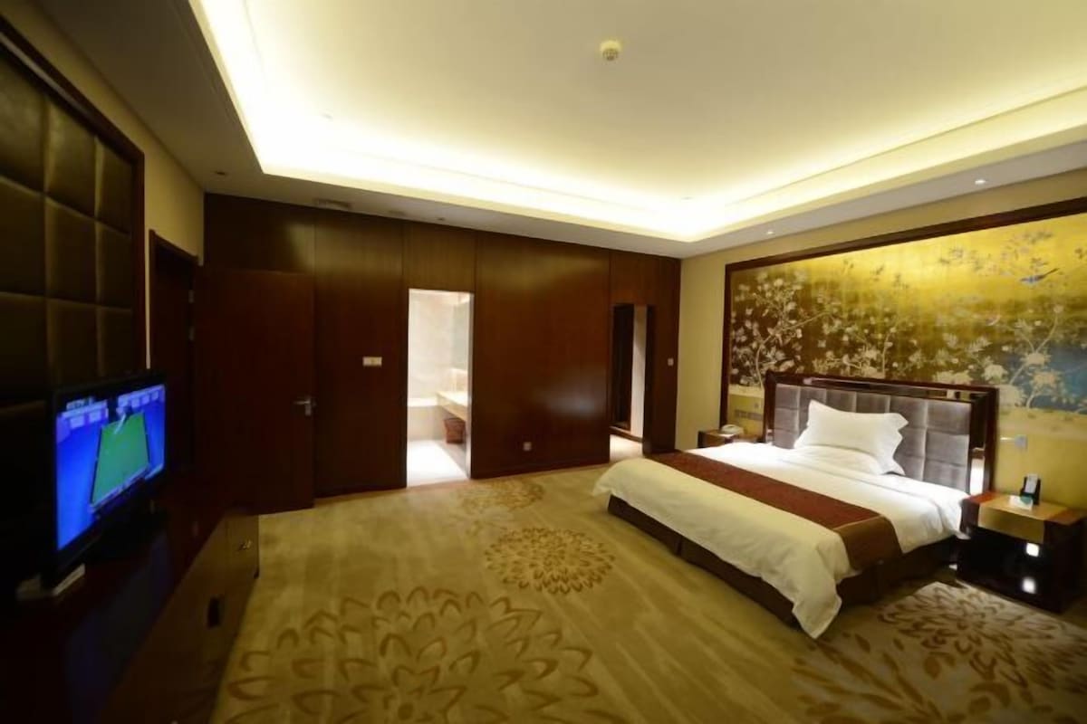 A hotel room with a large bed, a television, and a decorative wall.