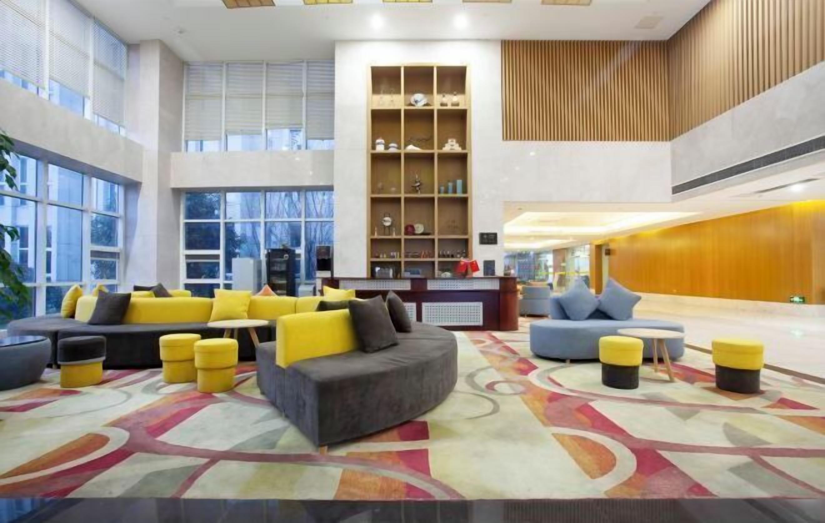 A spacious lobby with a central seating area, a reception desk, and a decorative shelving unit.
