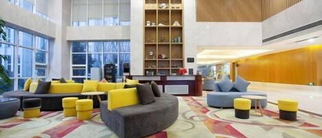 A spacious lobby with a central seating area, a reception desk, and a decorative shelving unit.