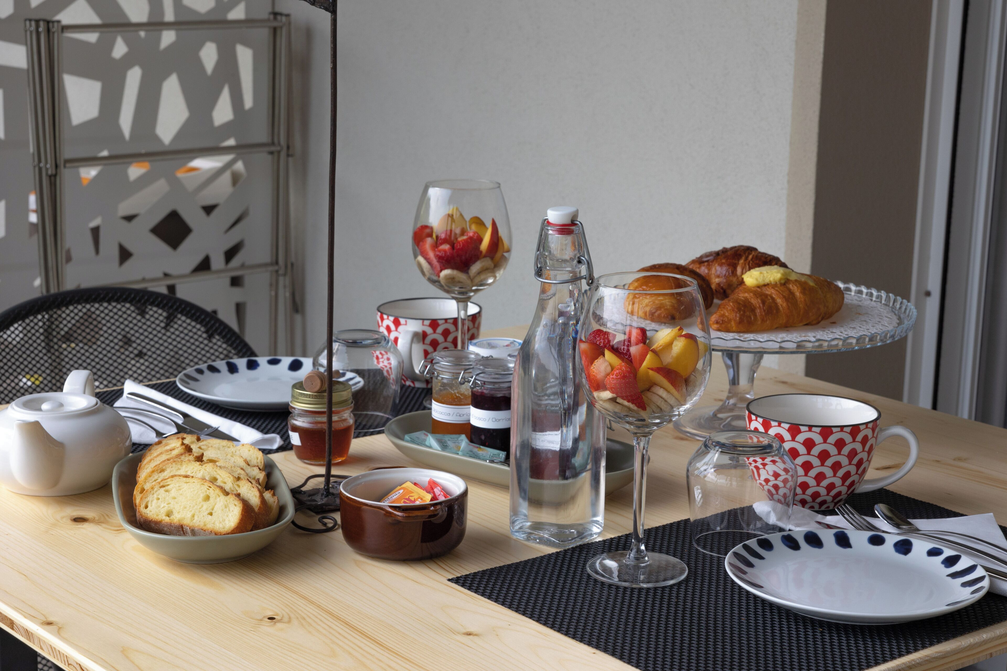 Mesa de café da manhã com croissants, frutas e chá.