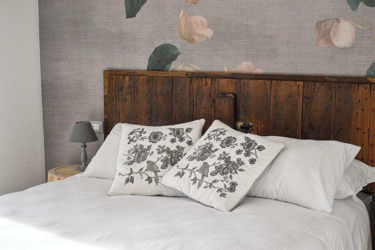 A bed with white bedding and two decorative pillows with floral patterns.