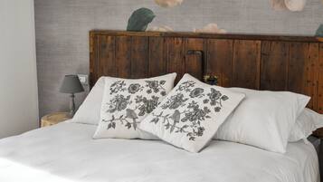 A bed with white bedding and two decorative pillows with floral patterns.