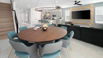 A modern dining area with a round table, teal chairs, and a central light fixture.