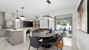 Una cucina moderna con isola centrale, zona pranzo con sedie e un'ampia finestra.