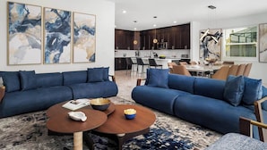 Una sala de estar moderna con dos sofás azules, una mesa de centro y arte abstracto en la pared.