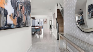 A modern interior with a staircase, a dining area, and a hallway leading to a bedroom.
