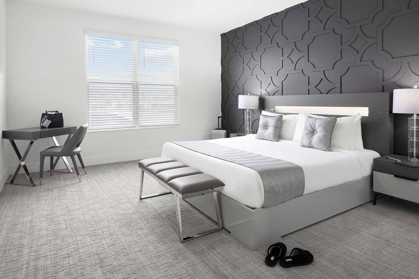 Une chambre d’hôtel moderne avec un grand lit, un bureau et une chaise.