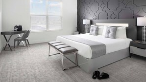 A modern hotel room with a large bed, a desk, and a chair.