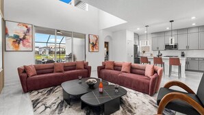 A modern living room with two sofas, a coffee table, and a dining area with chairs.
