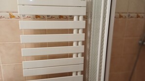 A bathroom with a white towel rack, a shower area, and tiled walls.
