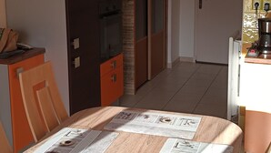 A compact kitchen with a dining area, featuring a wooden table, cabinets, and a refrigerator.