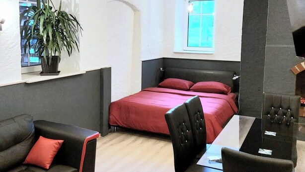 Une pièce de taille modeste comprenant un lit, un canapé, une table à manger et une plante en pot.